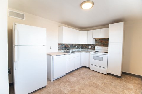 A kitchen with white appliances and a marble backsplash.